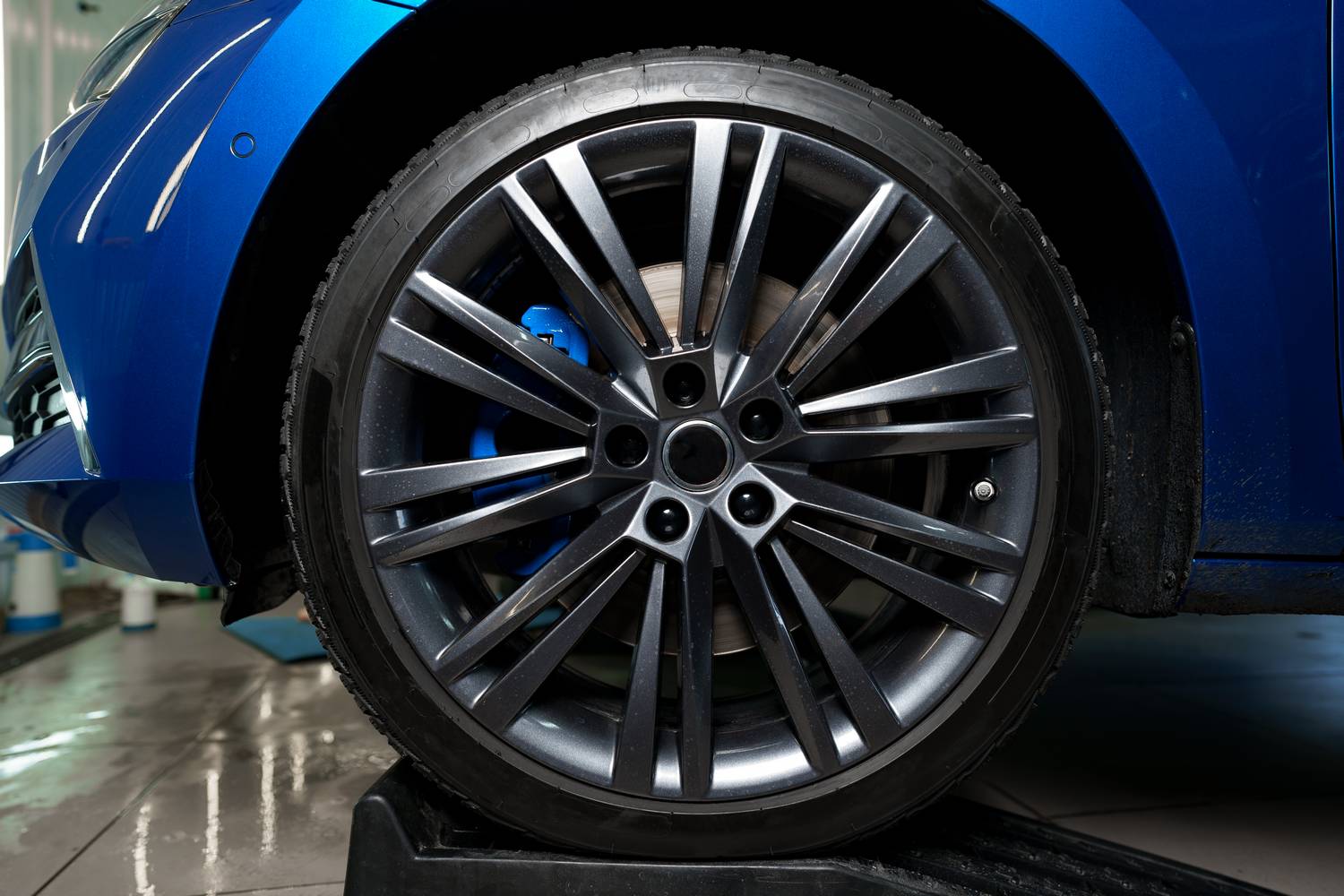 Front wheel of modern blue sport car, close up