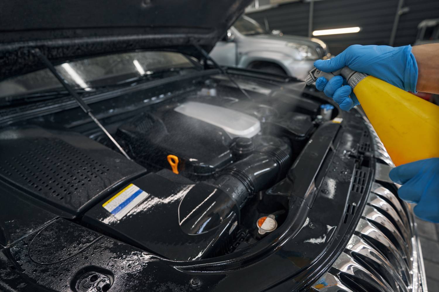 Cropped view of washing car engine by spraying special fluid in automobile repair service center